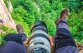 Man hiker and photographer at work sits on edge of mountain rock in Caucasus Mountains