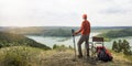 Man hiker relaxing by the top mountain and enjoying the view of valley with lake. Royalty Free Stock Photo