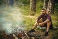 Man hiker roast sausages on stick on bonfire in forest