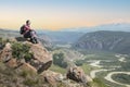 Man hiker sitting on cliff and enjoying valley view at sunset. Freedom concept. Royalty Free Stock Photo
