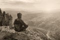 Man hiker sitting on top of mountain in meditation pose and thinking, black and white toned picture. Royalty Free Stock Photo