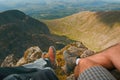 Man hiker sitting on the top of mountain rocks. Beautiful weather with Scotland nature. Detail of hiking boots on the difficult pa Royalty Free Stock Photo