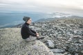 Man hiker sitting in a yoga pose at the peak of the mountain in the summer. Meditation after a long climb on a mountain