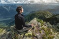 Man hiker sitting in a yoga pose at the peak of the mountain in the summer. Meditation after a long climb on a mountain