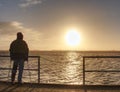 Man hiker stand alone and watching sunrise above sea bridge