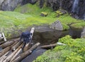 Man hiker standing on wooden log takeing up clean water, filling