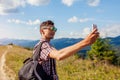 Man hiker taking selfie with smartphone in Carpathian mountains on hill peak. Traveler backpaker enjoys view