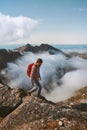 Man hiker trekking alone in mountains above clouds solo travel in Norway