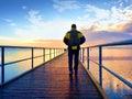 Man hiker walk on wet mole above sea to Sun. Fantastic morning Royalty Free Stock Photo