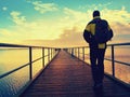 Man hiker walk on wet mole above sea to Sun. Fantastic morning Royalty Free Stock Photo