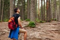 Man hiker walking through mountain forest path surrounded with roots in Carpathians. Traveler with backpack resting Royalty Free Stock Photo