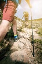 Man hiker walking on mountain rocks with sticks. Beautiful weather with Scotland nature. Detail of hiking boots on the difficult p Royalty Free Stock Photo