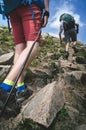 Man hiker walking on mountain rocks with sticks. Beautiful weather with Scotland nature. Detail of hiking boots on the difficult p