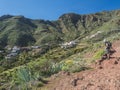 Man hiker watching at scenic landscape with Imada village at hiking trail Barranco de Guarimiar Gorge. Green mountain