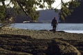 Man hikes on Galiano Island British Columbia beach near the ocean and forest with walking stick