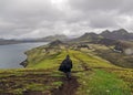 Man hiking alone into the wild admiring volcanic landscape with heavy backpack. Travel lifestyle adventure wanderlust concept Royalty Free Stock Photo