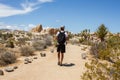 Man hiking with backpack between boulders and joshua trees on Arch Rock Trail in Joshua Tree National Park, CA, USA Royalty Free Stock Photo