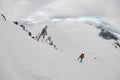 Man with the hiking equipment climbing up on the snow on the mountain hill