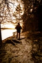 Man hiking in forest by frozen lake during sunrise in winter Sweden Royalty Free Stock Photo