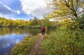 Hiker walking next to the lake in autumn forest.