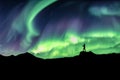 Man hiking on mountain with northern lights explosion Royalty Free Stock Photo