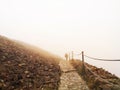 Man hiking on a mountain path surrounded by thick white mist