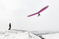 Man on the hill looks at the flying hang glider wing