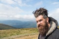 Man hipster with long beard hair on mountain landscape