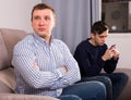 Man with his adult son are conflicting and boy playing with phone Royalty Free Stock Photo