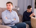 Man with his adult son are conflicting and boy playing with phone Royalty Free Stock Photo