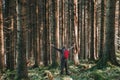 A man with his arms out stretched in a beautiful pine forest on a sunny winters day, Elan Valley, Wales, UK