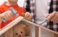 Man and his child playing builders with wooden doll house at home Royalty Free Stock Photo