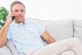 Man on his couch making phone call and smiling at camera Royalty Free Stock Photo