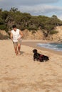 Man with his dog running on a beach with lush trees in the background. Royalty Free Stock Photo