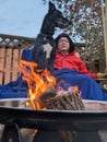 A man and his Great Dane dog sit on a swing together by a fire outside Royalty Free Stock Photo