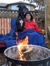 A man and his Great Dane dog sit on a swing together by a fire outside Royalty Free Stock Photo