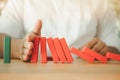 Man his hands stopping the red domino falling into green domino Royalty Free Stock Photo