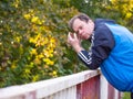 Man with his head in his hands and leaning on the railing, worried and sad Royalty Free Stock Photo