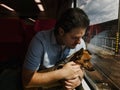 Man and his little mixed breed dog travelling in a train