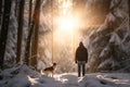 A man and his pet dog walking though a snowy forest on sunny winter day. Adventurous young man and his dog on a walk. Hiking and