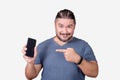 A man in his 30s endorsing a smartphone. Pointing to the cellphone with his index finger. Advertising an app Royalty Free Stock Photo