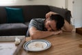 Sad latin man asleep on the table next to an empty food plate Royalty Free Stock Photo