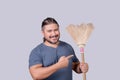 A man in his 30s pointing to an old broom. A househusband doing the the house cleanup. Cleanliness concept