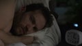 Man in his 40s suffering insomnia, turning in bed and looking angrily at clock