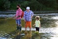 Man with his son and father on river fishing with fishing rods. Boy with father and grandfather fly fishing outdoor over Royalty Free Stock Photo