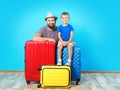 Man and his son with suitcases near color wall