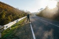 Man hitchhiking on a country road. Traveler showing thumb up on for hitchhiking during road trip. Royalty Free Stock Photo
