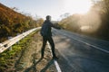 Man hitchhiking on a country road. Traveler showing thumb up on for hitchhiking during road trip. Royalty Free Stock Photo