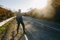 Man hitchhiking on a country road. Traveler showing thumb up on for hitchhiking during road trip. Royalty Free Stock Photo