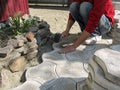 Man hits the surface of a gray concrete paving slab, laying it on a dry sand-cement mix in yard. Concept of laying paving tiles, Royalty Free Stock Photo